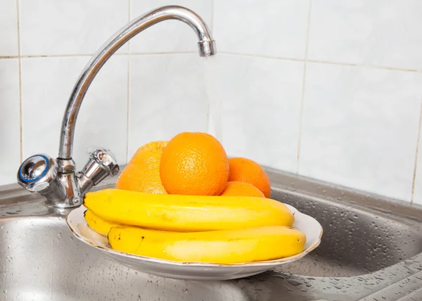 Wash fruits under running water — Stock Photo, Image
