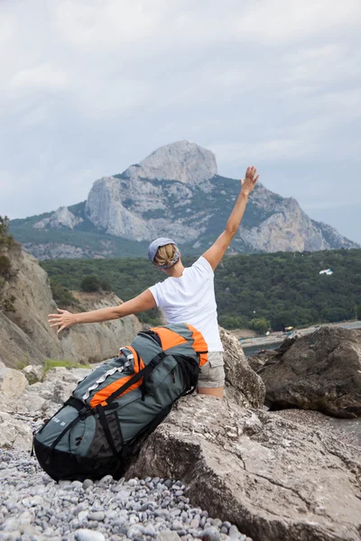 Joven mujer feliz con mochila relajante en una roca —  Fotos de Stock