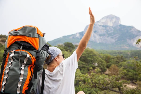 Junge glückliche Frau mit Rucksack entspannt auf einem Felsen — Stockfoto