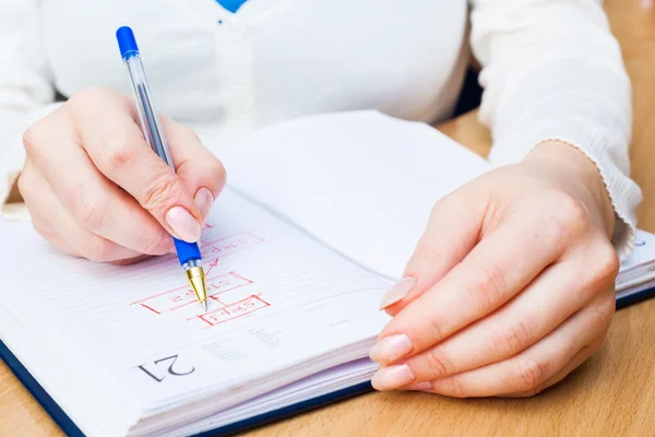 Geschäftsfrau schreibt mit Stift in Notizblock — Stockfoto