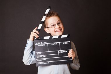 Little boy holding clapper board in hands.
