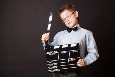 Little boy holding clapper board in hands.