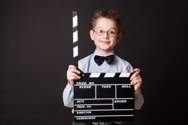 Little boy holding clapper board in hands.