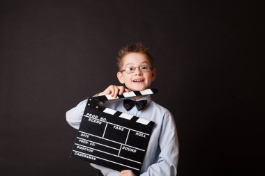 Little boy holding clapper board in hands.