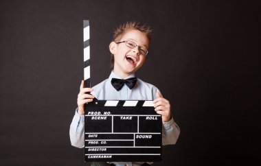 Little boy holding clapper board in hands.