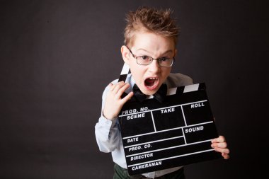 Little boy holding clapper board in hands.
