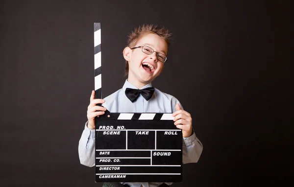 Little boy holding clapper board in hands.