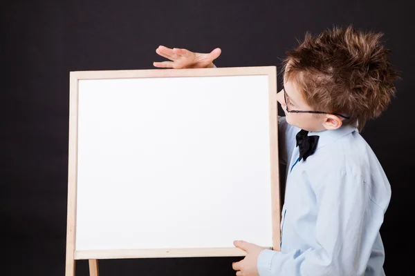 Portrait of cheerful boy pointing on white banner — Stock Photo, Image