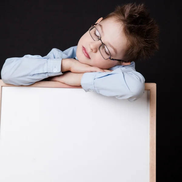 Portrait of cheerful boy pointing on white banner — Stock Photo, Image