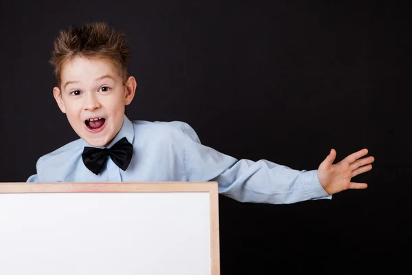 Portrait of cheerful boy pointing on white banner — Stock Photo, Image