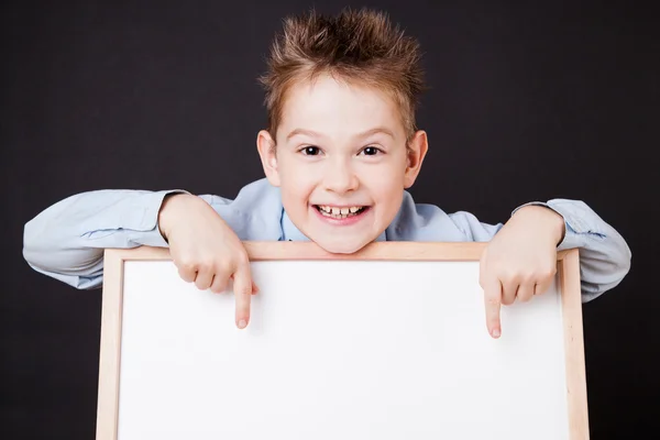 Portrait of cheerful boy pointing on white banner — Stock Photo, Image