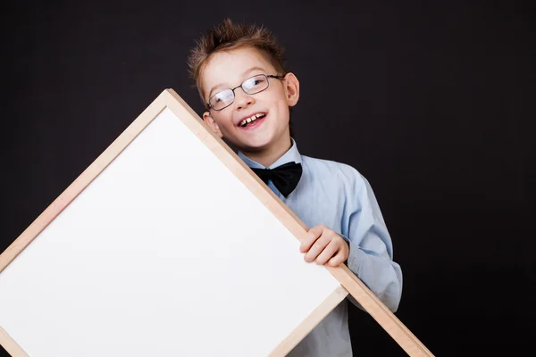Portrait of cheerful boy pointing on white banner — Stock Photo, Image