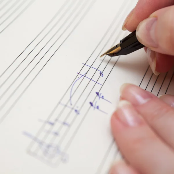 Hand with pen and music sheet — Stock Photo, Image