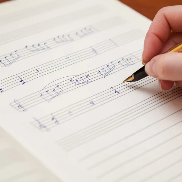 Hand mit Stift und Notenblatt — Stockfoto