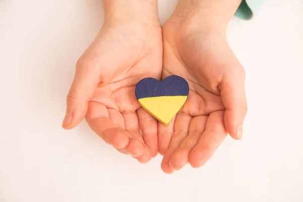 Vista de ángulo alto de las manos del niño sosteniendo la bandera ucraniana pintado corazón —  Fotos de Stock