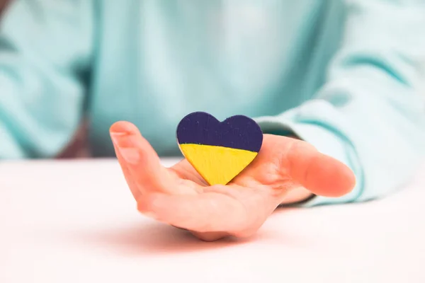 Vista ad alto angolo di bambino mani che tengono bandiera ucraina dipinto cuore — Foto Stock