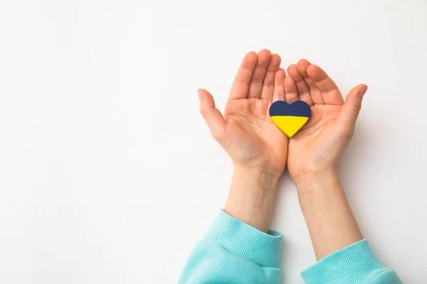 Vista de ángulo alto de las manos del niño sosteniendo la bandera ucraniana pintado corazón — Foto de Stock