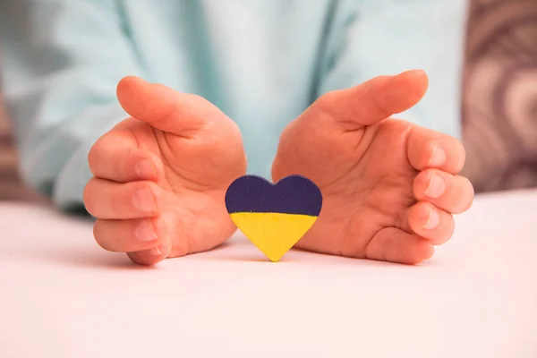 High angle view of child hands holding ukraine flag painted heart — Stock Photo, Image