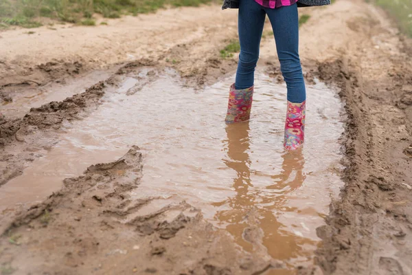 Smiling girls run through the puddles and play.
