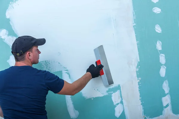壁に漆喰職人の手 仕上げパテとドライウォール上の労働者のトロールパテ ストック画像