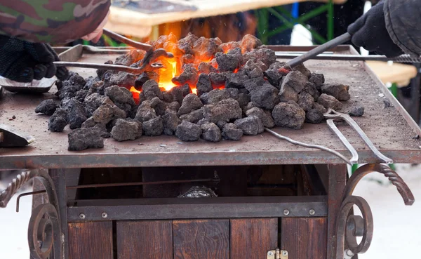 Řemeslník Kovář oteplování kus železa v ohni — Stock fotografie