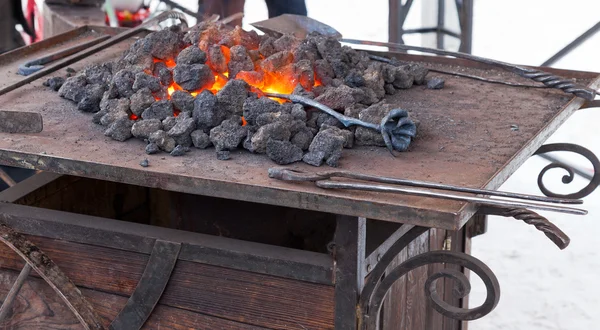 Artisan forgeron réchauffant un morceau de fer dans le feu — Photo