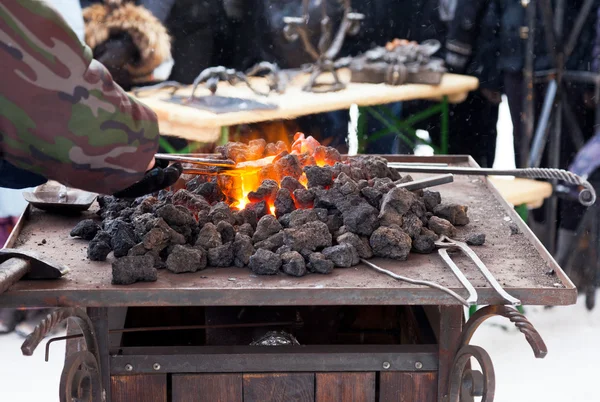 Hantverkare smeden värmer en bit järn i elden — Stockfoto