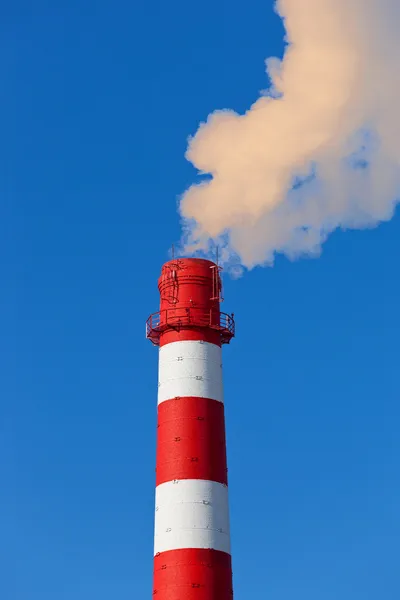 Chaminé de fábrica vermelha e branca com fumaça contra o céu azul — Fotografia de Stock