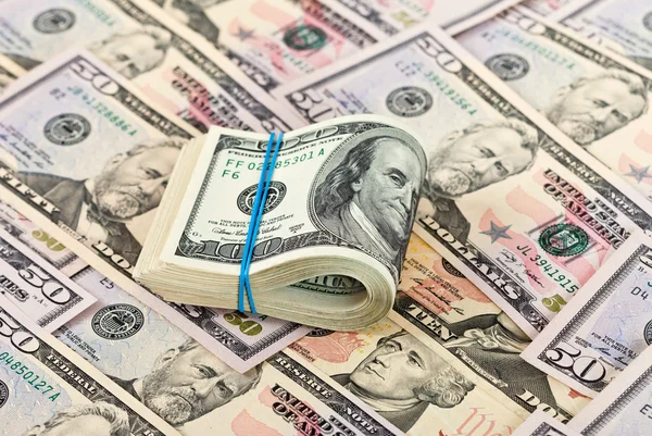 Gevouwen dollarbiljetten gewikkeld door rubber op geld achtergrond — Stockfoto