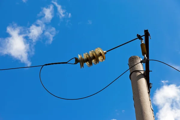 Electric power post with wire against bright blue sky and clouds — Stock Photo, Image