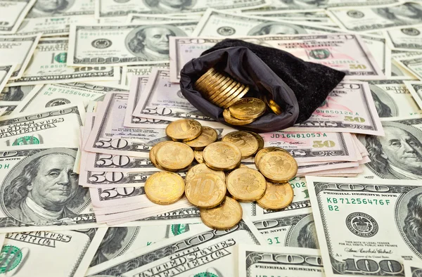 Bolsa llena de monedas sobre fondo de billetes de EE.UU. —  Fotos de Stock