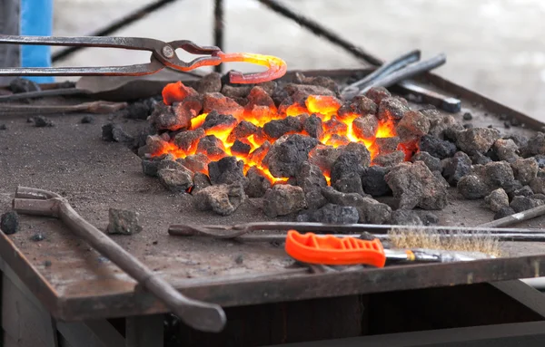 Handwerker Schmied wärmt ein Hufeisen aus Eisen im Feuer — Stockfoto