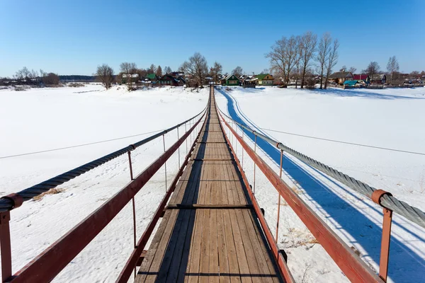 Ponte de suspensão sobre o rio congelado — Fotografia de Stock