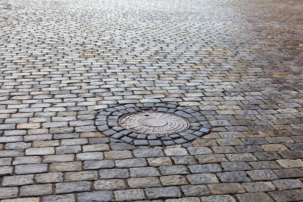 Old round steel sewer manhole on the cobblestone road — Stock Image Old round steel sewer manhole on the cobblestone road Stock Picture