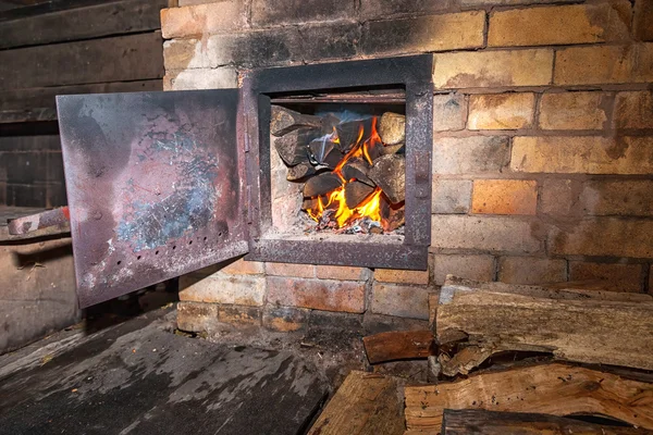 Gammal kamin med öppen dörr och bränna trä — Stockfoto