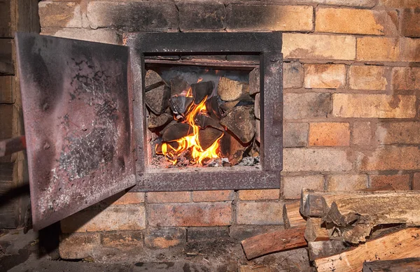 Gammal kamin med öppen dörr och bränna trä — Stockfoto