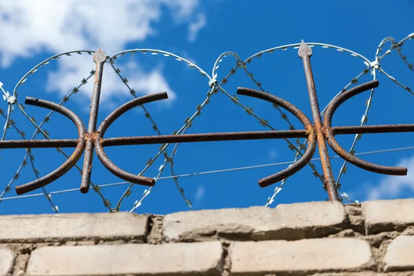 Taggtråd på staketet mot en ljus blå himmel — Stockfoto