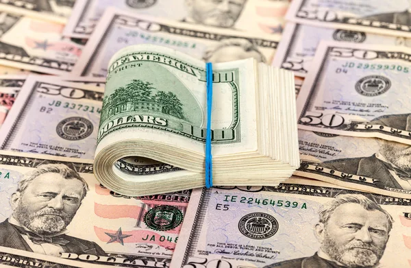 Contas de dólar dobrado envolto por borracha no fundo do dinheiro — Fotografia de Stock