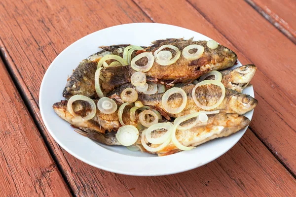 Fried fish with onion on the plate — Stock Photo, Image