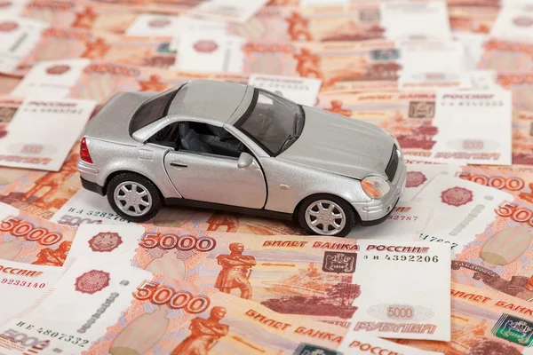 Игрушечный автомобиль на фоне российских банкнот — стоковое фото