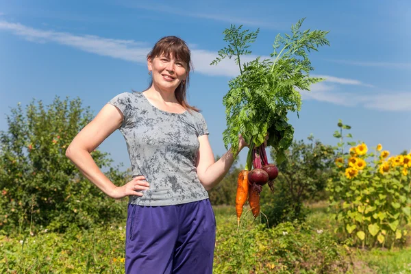 Ung kvinna med ett knippe grönsaker i handen — Stockfoto