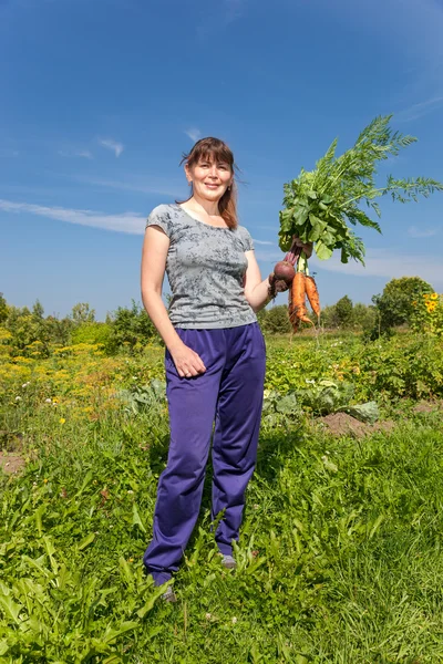 Young woman holding a sheaf of vegetables in the hand — Stock Photo, Image