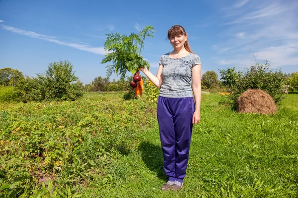 Young woman holding a sheaf of vegetables in the hand — Stock Photo, Image