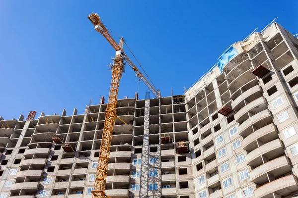 Edificios altos en construcción con grúa contra un cielo azul — Foto de Stock