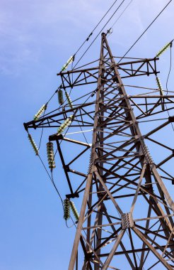 Mavi gökyüzüne karşı yüksek voltajlı elektrik kulesi