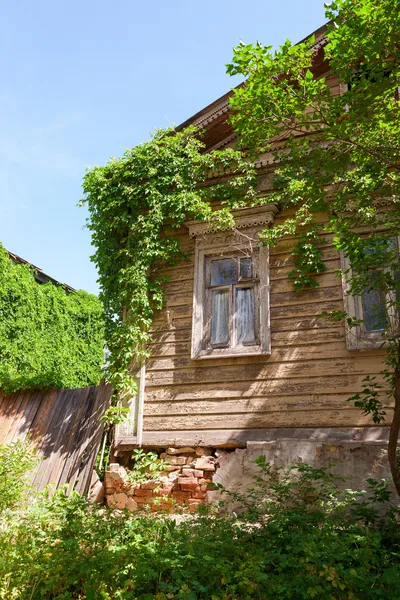 Yeşil bitkiler üzerine mavi gökyüzü ile eski ahşap ev — Stok fotoğraf