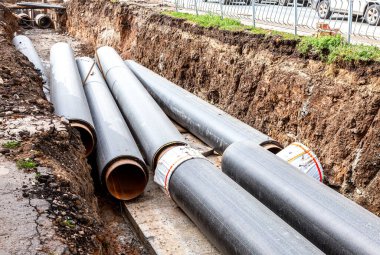 Isıtma borularının değiştirilmesi ve ısıtma sisteminin modernizasyonu. İnşaat, kazılmış hendek derinliğindeki büyük demir borular üzerinde çalışıyor.