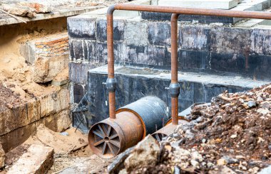 Isıtma borularının değiştirilmesi ve ısıtma sisteminin modernizasyonu. İnşaat, kazılmış hendek derinliğindeki büyük demir borular üzerinde çalışıyor.