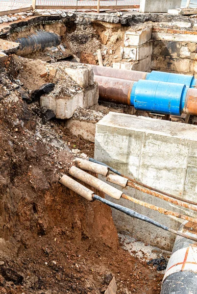 Isıtma borularının değiştirilmesi ve ısıtma sisteminin modernizasyonu. İnşaat, kazılmış hendek derinliğindeki büyük demir borular üzerinde çalışıyor.