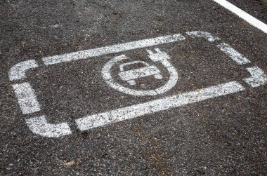 Asfalt yolda elektrikli araç şarj istasyonu tabelası